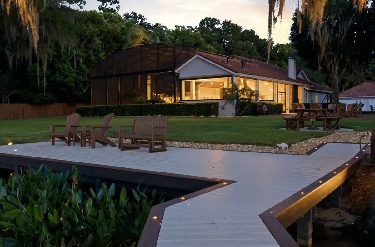 Backyard deck at dusk with Adirondack chairs and a glowing screened lanai