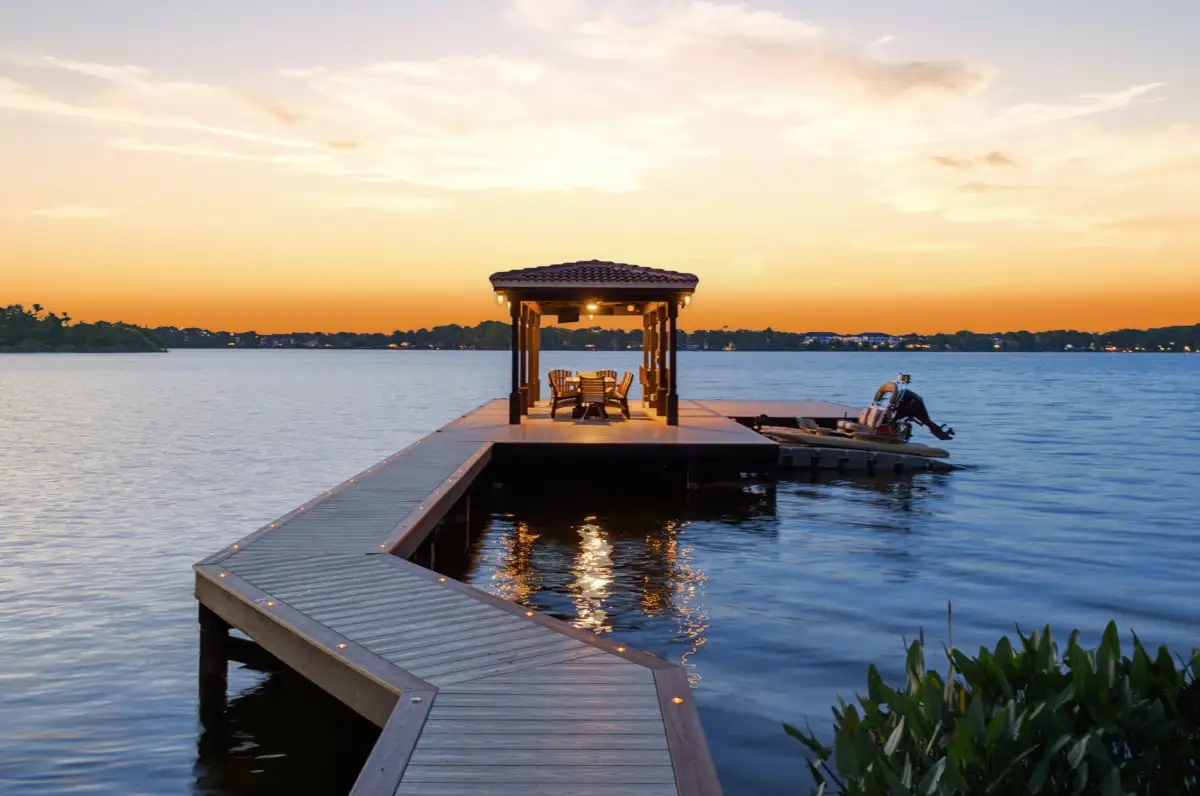 Private boat dock with a covered gazebo on a calm lake at sunset