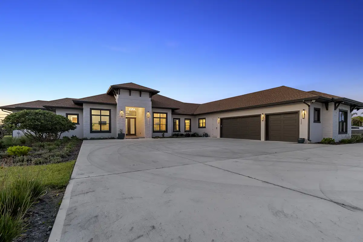 Single-story estate photographed at dusk with a lit entry and curved driveway