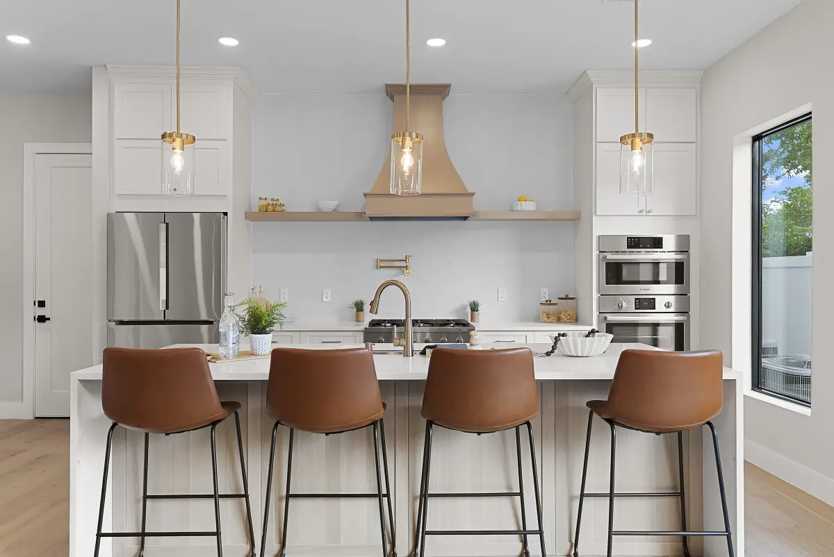 Straight-on view of a white kitchen with a wood hood and double wall oven