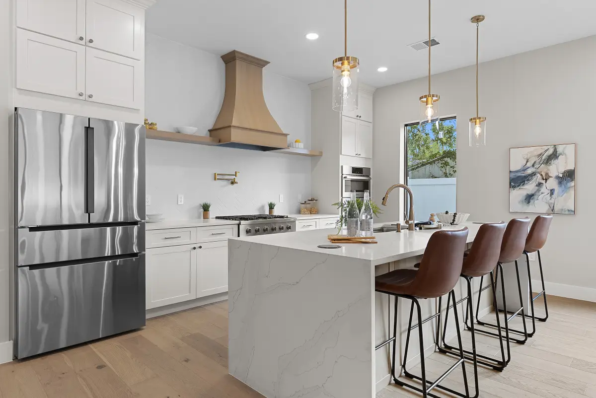 Kitchen with a wood range hood, stainless refrigerator, and leather bar stools