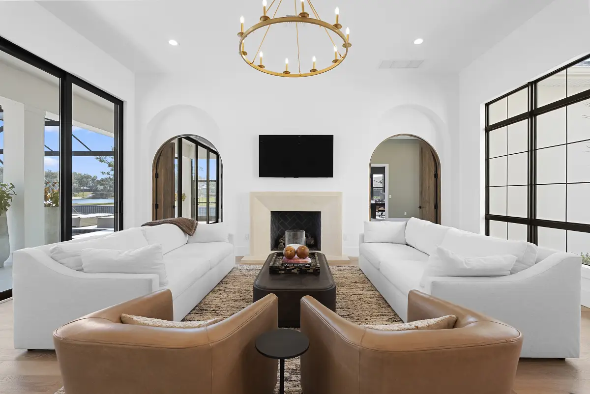 Living room with paired white sofas, tan leather swivel chairs, and a fireplace